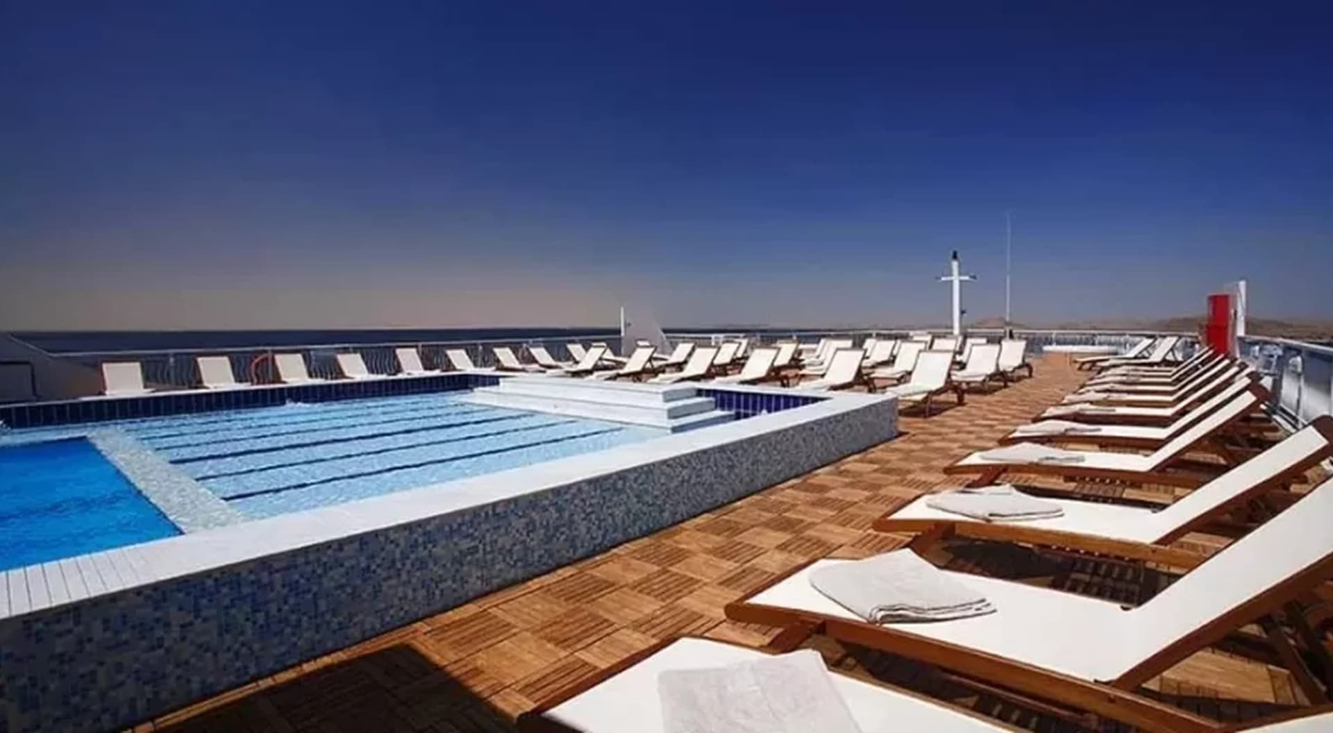 Piscina y tumbonas en la cubierta de un barco, al anochecer
