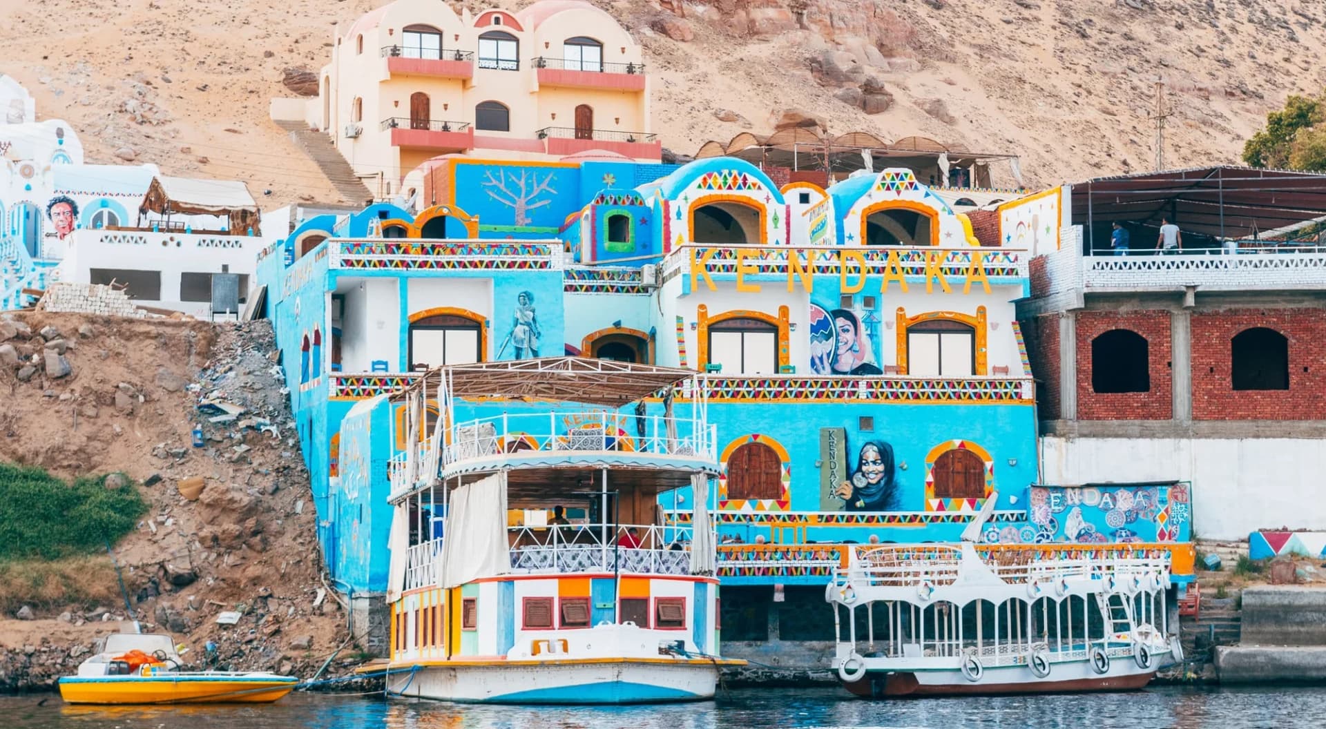 Casas de colores de una aldea nubia junto al Nilo, con barcos amarrados en la orilla